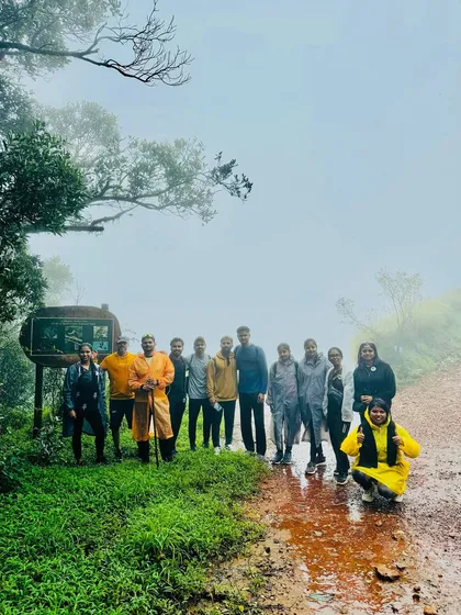 Our trekking group posing by a trail marker in the misty weather of the Kurinjal trek in Kudremukha National Park.