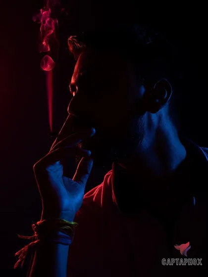 A close-up low-light portrait that plays with shadow and color. The rim lighting defines the subject's form while keeping most of the features in mystery, adding to the creative and moody atmosphere.