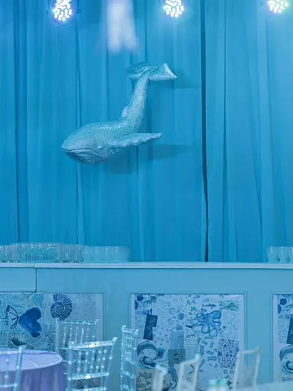 The bar area was transformed into a deep-sea scene with blue drapery and a majestic whale prop. Even functional areas of an event are styled to maintain the thematic illusion.