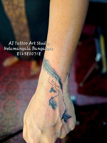 A feather dissolving into a string of beads and flying birds, a beautiful wrist tattoo.
