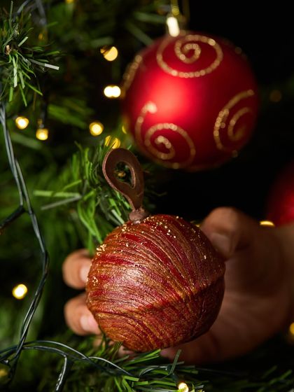 Our edible Maska Rum Bauble hanging on a Christmas tree. It's a playful and delicious addition to your holiday decorations.