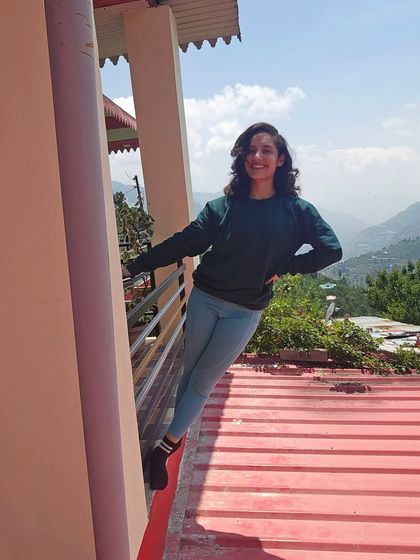 Leaning against the balcony pillar, with the mountain slopes visible in the distance. It’s a great place to get your dose of Vitamin D.