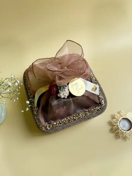 This festive potli-style hamper is wrapped in delicate organza and adorned with a golden "Happy Diwali" tag. It's a beautiful and traditional way to present your gifts.