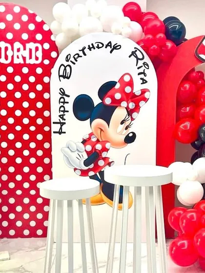 A classic Minnie Mouse theme for a 2nd birthday celebration. The setup includes red and white polka-dot backdrops, a Minnie cutout, a large number '2', and balloon arrangements in red, black, and white.