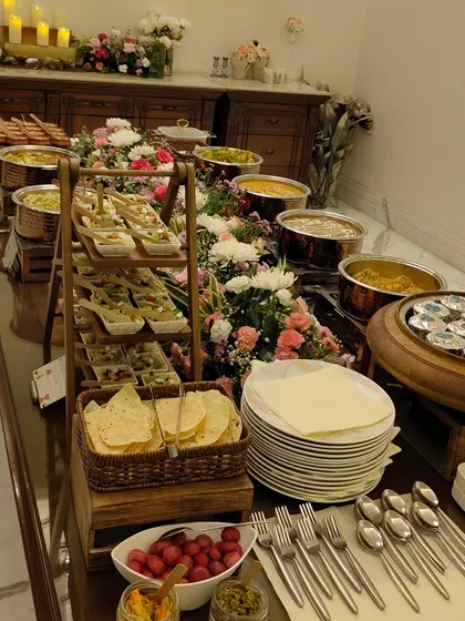 A beautifully arranged buffet table ready for a Diwali party. With appetizers on tiered stands and main courses in copper pots, this setup promises a seamless and elegant dining experience.