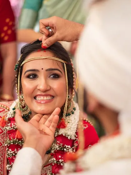 A close-up of a blessing ritual, capturing the bride's joyful and slightly emotional expression.