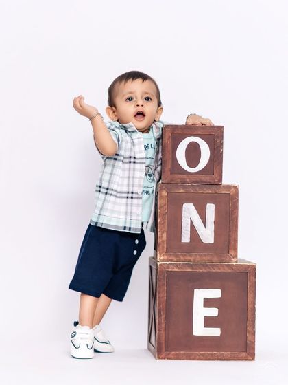 This toddler is proudly standing by his "ONE" blocks, marking his first birthday. We provide a variety of outfits and props for our studio milestone sessions.