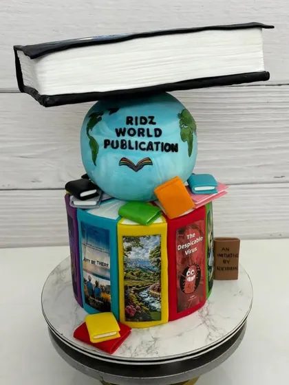 A different angle of the topsy-turvy book cake, showing the colorful, edible book spines and the globe.