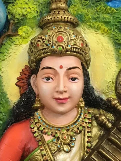 A close-up view of our Saraswati mural highlights the fine details our artists achieve. Notice the delicate facial expression, the intricate jewelry, and the crown, all sculpted and painted by hand to bring the deity to life.