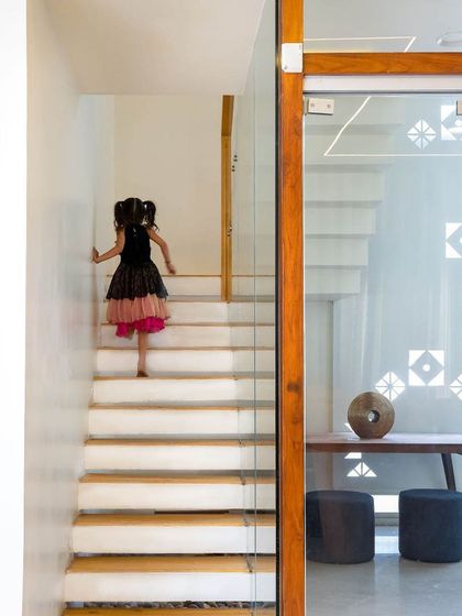 A child climbs a staircase with wooden treads and a glass railing, demonstrating how I consider human scale and proportion in every design detail.
