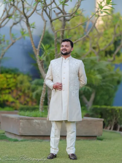 A classic full-length outdoor portrait of the groom, standing confidently in a garden setting.