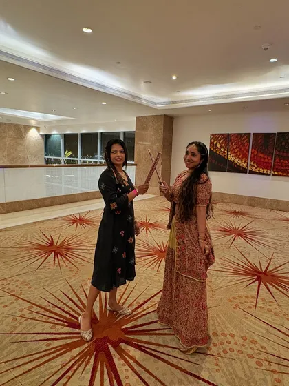 A fun moment posing with dandiya sticks before the main event begins. The festive spirit is contagious.