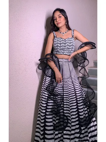 A full-length view of this chic black and white lehenga. The makeup and hair are designed to be modern and elegant, perfect for an engagement party or a stylish Sangeet night.