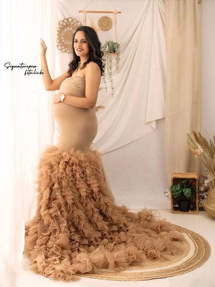 A full-length portrait by the window, showcasing the dramatic train of the ruffled gown against the soft curtains.