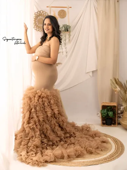 A full-length portrait by the window, showcasing the dramatic train of the ruffled gown against the soft curtains.
