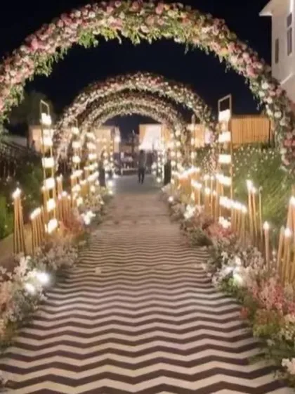 A beautiful floral tunnel entrance for an evening wedding. The arches are covered in flowers and lit with candles, creating a romantic and inviting path.