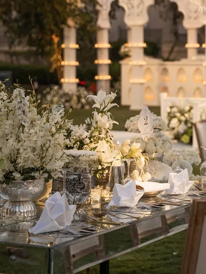 Attention to detail is key, as seen in this 'Sheesh Mahal' reception tablescape featuring mirrored tables and lush all-white floral arrangements for a sophisticated look.