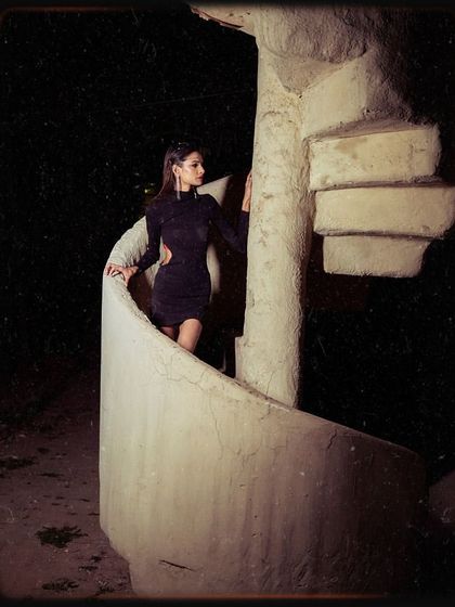 A creative shot from the portfolio, using a spiral staircase as a prop. The model is styled in a sleek black cutout dress, creating a modern and edgy look.