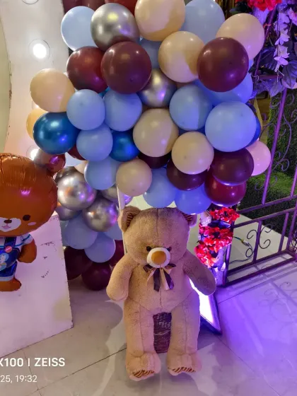 Themed props for the teddy bear party, including a large stuffed bear and a character foil balloon.