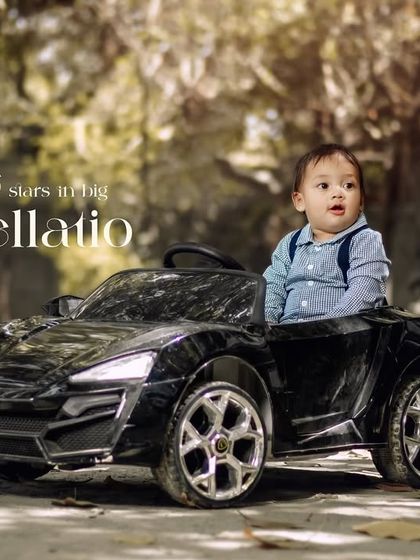 Little stars in big constellations. A toddler in suspenders takes a ride in his toy car on a wooded path.