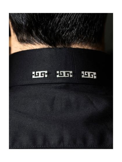The details on the back of the collar. These small, metallic embellishments add a subtle, modern edge to a classic black garment, a signature of our design philosophy.