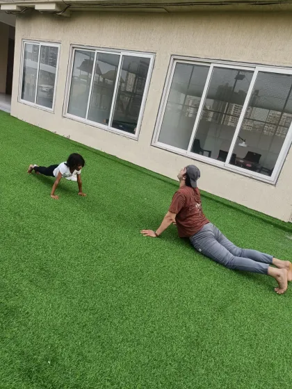 I lead by example. Here, I'm demonstrating the Upward-Facing Dog pose while a young student practices her push-ups. We build strength and flexibility together.