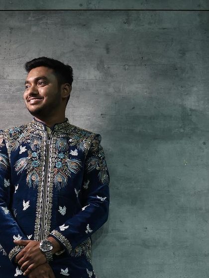 Another shot of the client in the royal blue velvet sherwani, showcasing the detailed bird-motif embroidery.