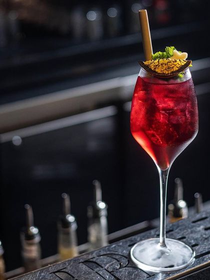 Indulge in an escapade of exquisite drinks. This vibrant red cocktail, served in a wine glass, is a result of our extensive mixology testing and curation.
