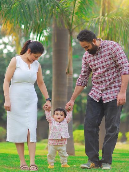 Those first wobbly steps are a precious memory. We captured this sweet moment as parents help their little one walk during her first birthday photoshoot in the park.