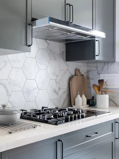 This kitchen, designed in collaboration with Muse Lab, features a beautiful hexagon tile backsplash. The dark grey upper cabinets and warm wood lower cabinets create a sophisticated and balanced look.
