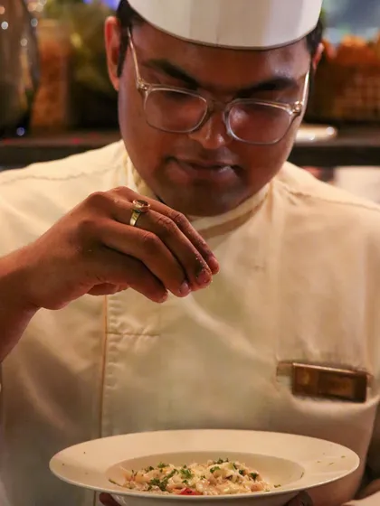 A chef adds the final seasoning to a dish, a moment of precision that ensures every plate is perfect before it leaves the kitchen.