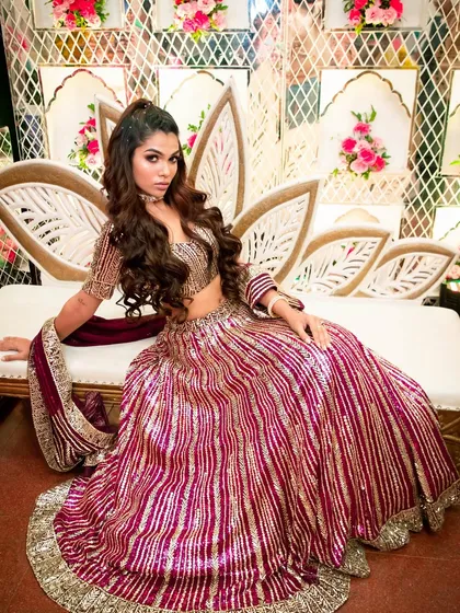 Seated on a floral throne, this bride looks every bit the modern royal. Her glamorous makeup completes the look, ensuring she is the center of attention.