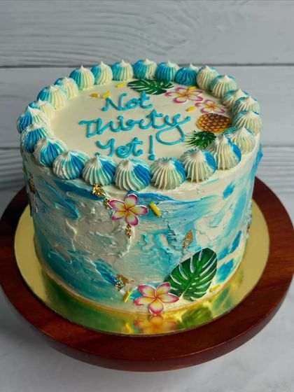 Aloha! This tropical-themed cake with a blue watercolor finish and edible flowers says "Not Thirty Yet!" It's a fun and beachy way to celebrate a birthday.