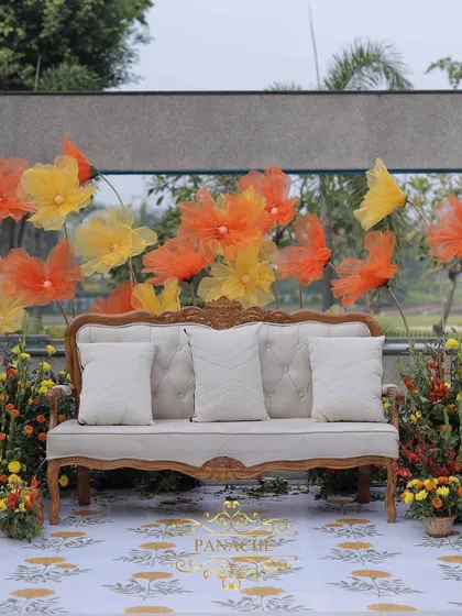 A frontal view of the couple's seating, showcasing the printed carpet and the whimsical organza flower backdrop.