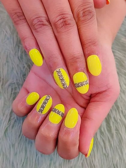 A bright and fun set of neon yellow nails with a contrasting black lace-like pattern.