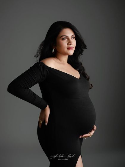 A classic and sophisticated portrait in a simple black gown, where the focus is entirely on the mother's confident gaze and beautiful form.