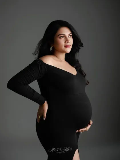 A classic and sophisticated portrait in a simple black gown, where the focus is entirely on the mother's confident gaze and beautiful form.