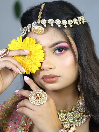 A playful and artistic shot for a pre-wedding portfolio. The use of a flower to frame the eye highlights the colorful makeup and adds a creative touch.