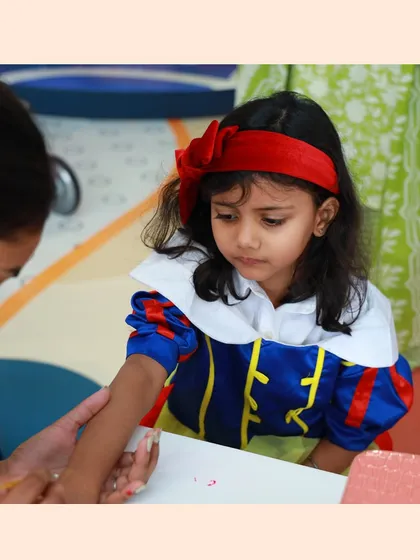 A little girl dressed as Snow White gets a temporary tattoo, adding to her costume.