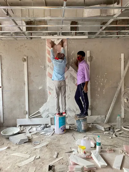 A behind-the-scenes shot of artisans at work, installing intricate marble inlay on a wall. This image captures the craftsmanship and manual skill that are essential to achieving high-quality design details.