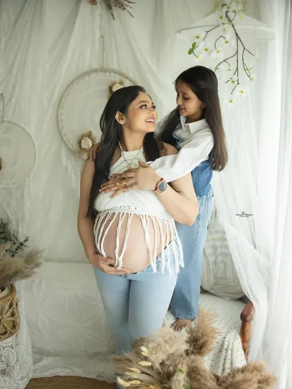 A sweet and quiet moment between a mother and her daughter. The natural, light-filled setting and casual denim outfits create a relaxed and authentic family portrait.