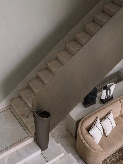 A gracefully curving staircase with a minimalist metal handrail is a sculptural element in the home.