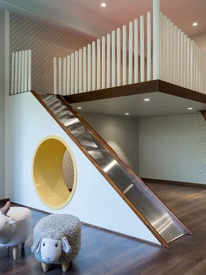 We believe children's rooms should be spaces for imagination to take flight. This custom-designed room features an elevated bed with an integrated slide and a cozy nook below, encouraging both play and rest. The use of soft hues and whimsical patterns creates a joyful yet calming atmosphere for growth and creativity.