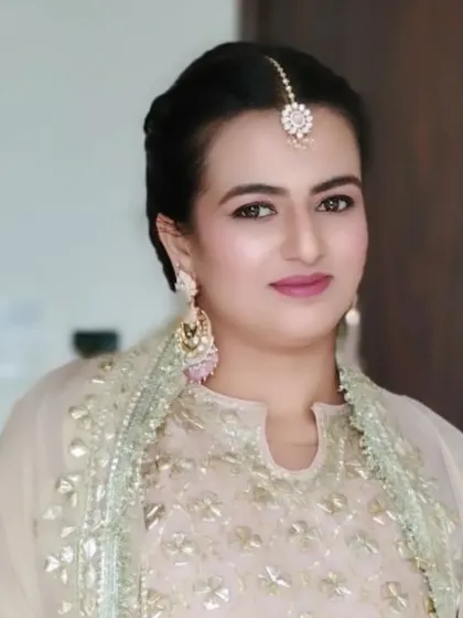 The front view of the client with her hair styled in a chic bubble braid. The hair is pulled back neatly, highlighting her makeup and maang tikka.