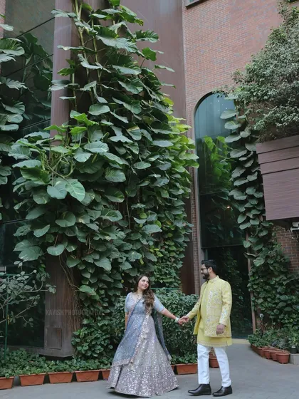 A romantic wedding portrait of the couple holding hands, framed by the lush greenery and modern architecture.