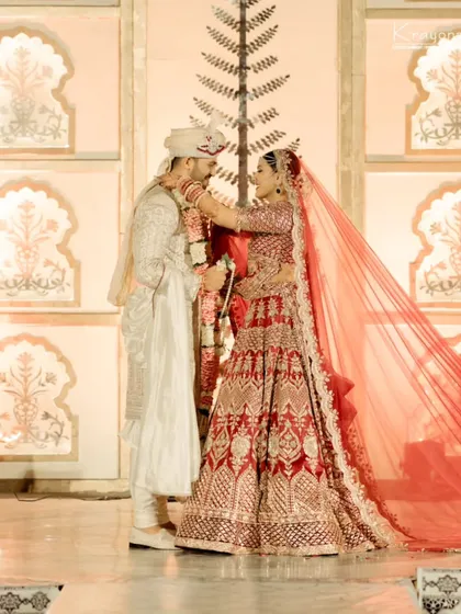 A tender moment during the varmala ceremony, as the bride lovingly places the garland on the groom.