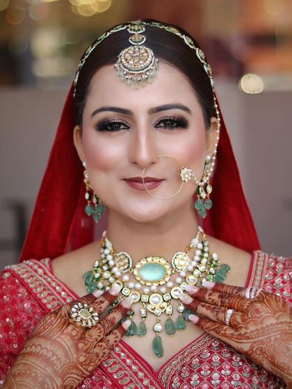 A close-up of a bride with beautiful pastel green and pearl jewelry. The makeup is soft and luminous, with a focus on clean skin and defined eyes.