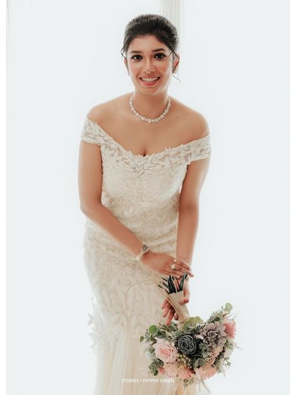 An elegant portrait of the bride in her off-the-shoulder gown, her pose graceful and her smile warm.