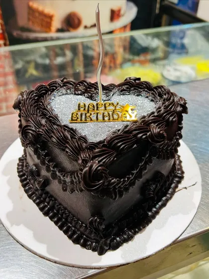 A heart-shaped chocolate cake with a silver glitter top, perfect for a birthday or anniversary.