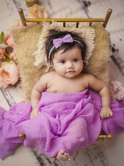 A little princess in her purple bed. This awake shot captures a beautiful, curious expression.